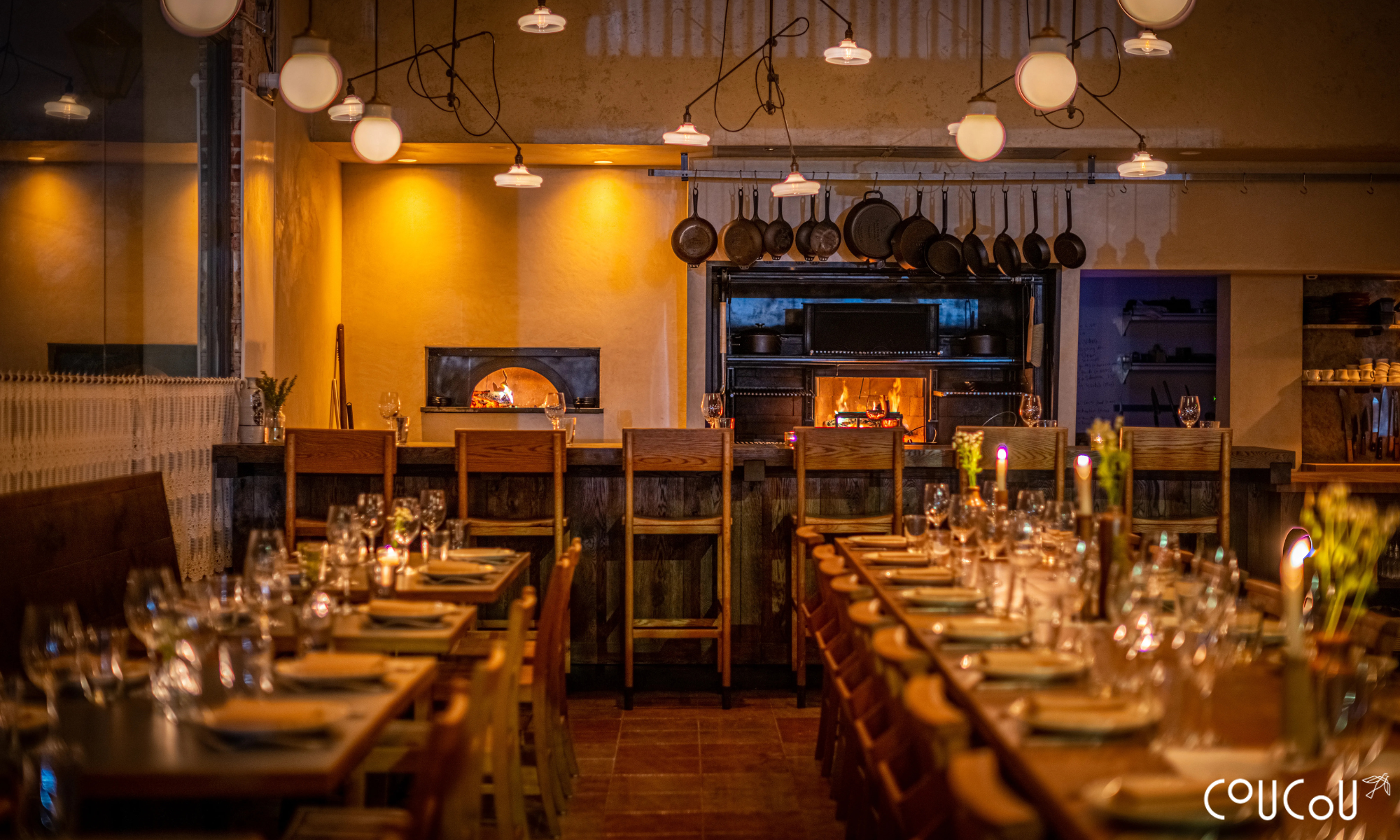 Restaurant dining room set for dinner service with a wood-fired oven at the back